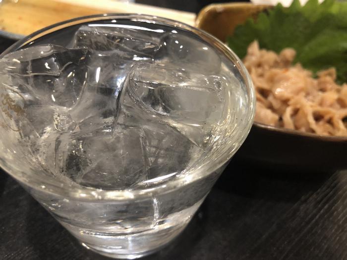 琥珀色に輝くブランデー梅酒が氷の入ったロックグラスに注がれ、梅の実が添えられている