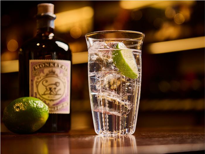 プロの技、炭酸水をグラスの縁に沿って静かに注ぎ、梅酒ソーダを作る様子のクローズアップ写真