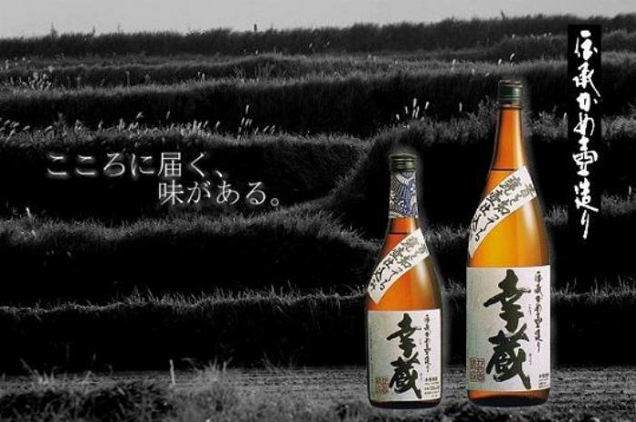 琥珀色に美しく熟成が進んでいる自家製梅酒が入った大きなガラス瓶。日付のラベルが貼られている。
