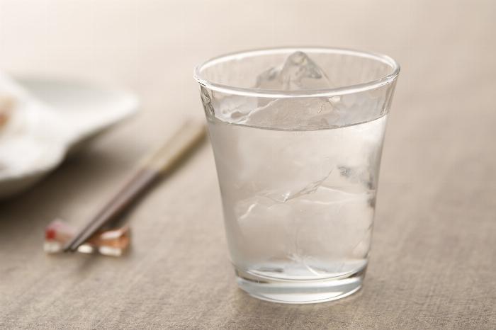 氷が入ったグラスに注がれた梅酒のロックと和風のおつまみが添えられたテーブル