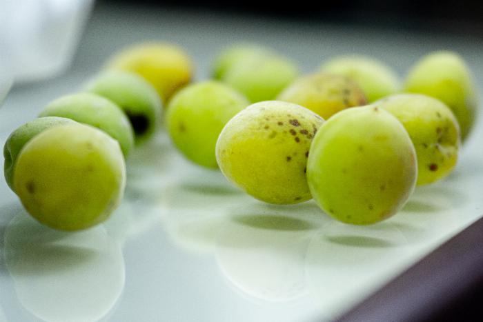 少量の梅酒を作るためにガラス瓶に青梅と氷砂糖を交互に詰める様子